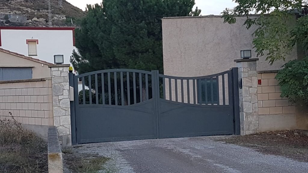 Puerta batiente metálica gris de dos hojas en entrada de vivienda