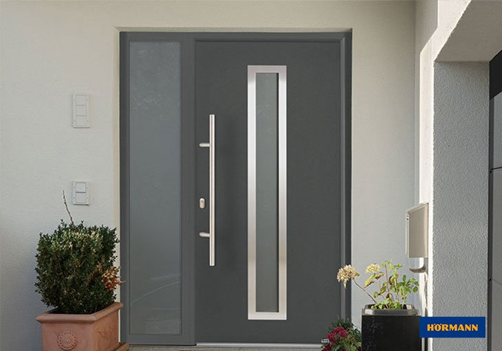 Puerta de entrada Hörmann gris con cristal vertical y fijo lateral